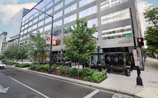 Street view of 2033 K Street NW in Washington DC showing modern office building with retail frontage and outdoor patio seating.